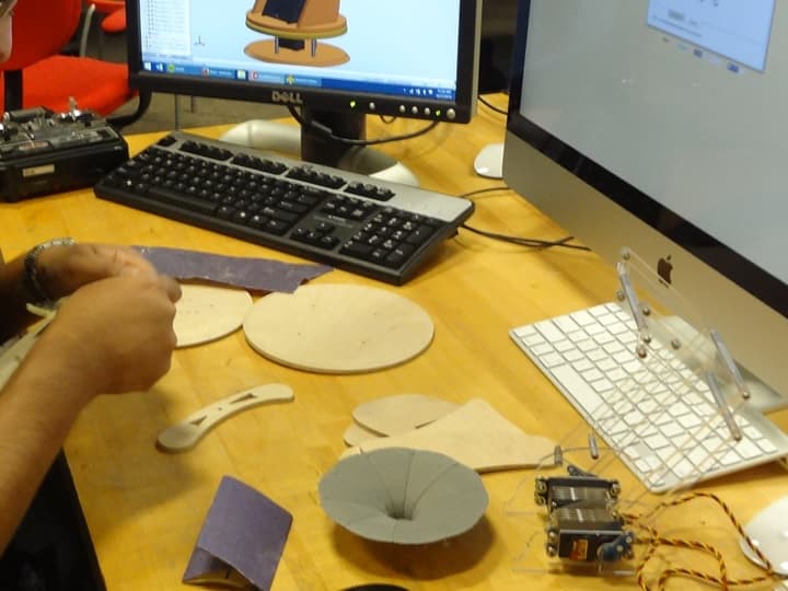 Various water-jet and 3D-printed components being assembled by hand.